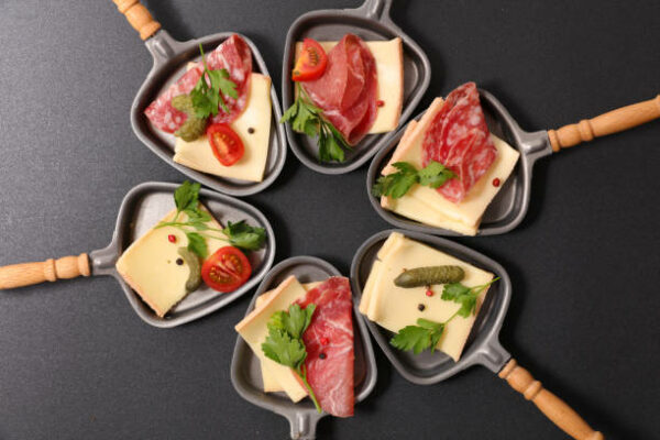 six coupelles à raclette remplies de fromage et charcuterie - IStock