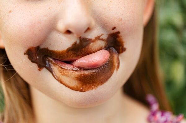 fille sourire tire la langue avec chocolat autour de la bouche