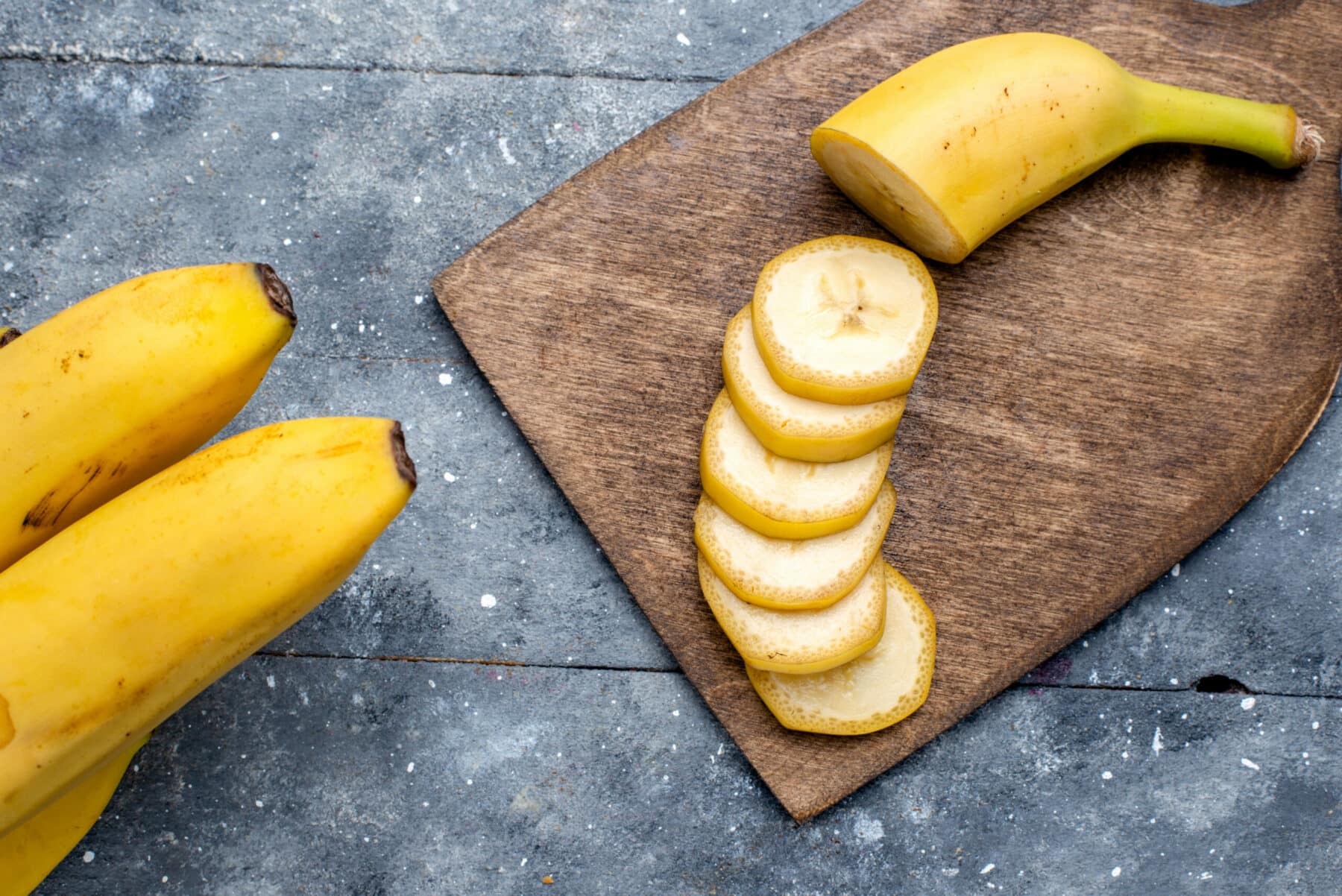 bananes et tranches de banane sur planche en bois