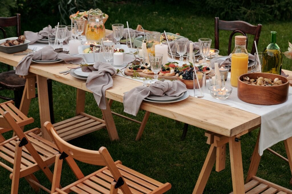 chaises en bois et table dressée avec nourriture dans l'herbe