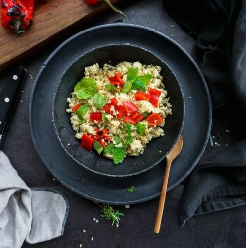 taboulé de quinoa dans assiette noire sur fond sombre