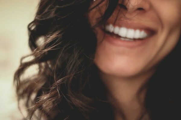 femme souriante à pleine dents cheveux bruns