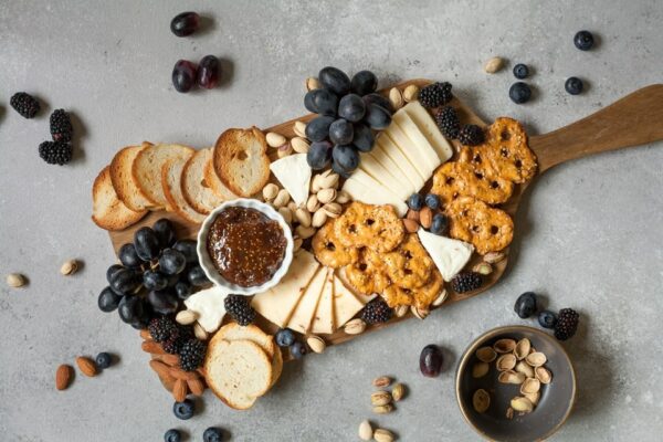 plateau de fromage avec fruits sur planche en bois et fond gris