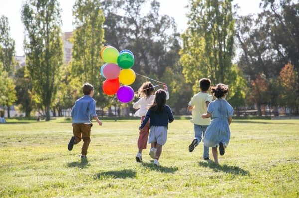 enfants qui courent dehors avec ballons colorés