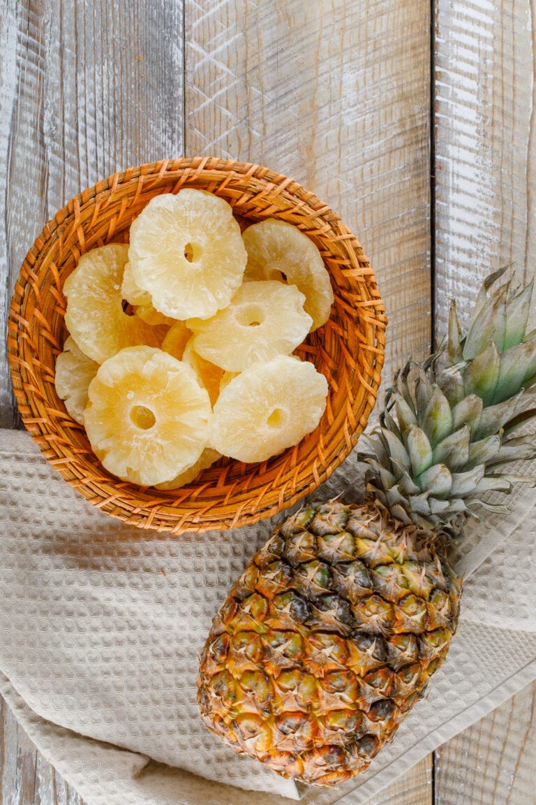 Tranches d'ananas confites et ananas sur fond bois - Freepik